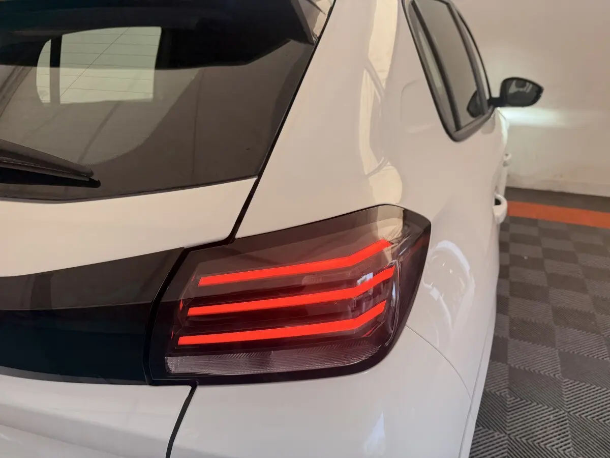 Feu arrière droit allumé d'une Peugeot 208 blanche vue en léger angle arrière dans un garage.