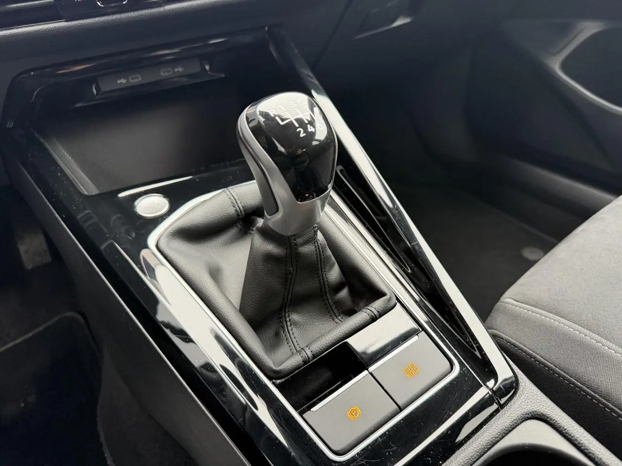 Gros plan sur la commande de boîte manuelle noire avec soufflet cuir dans l'habitacle gris de la Volkswagen Golf VIII.