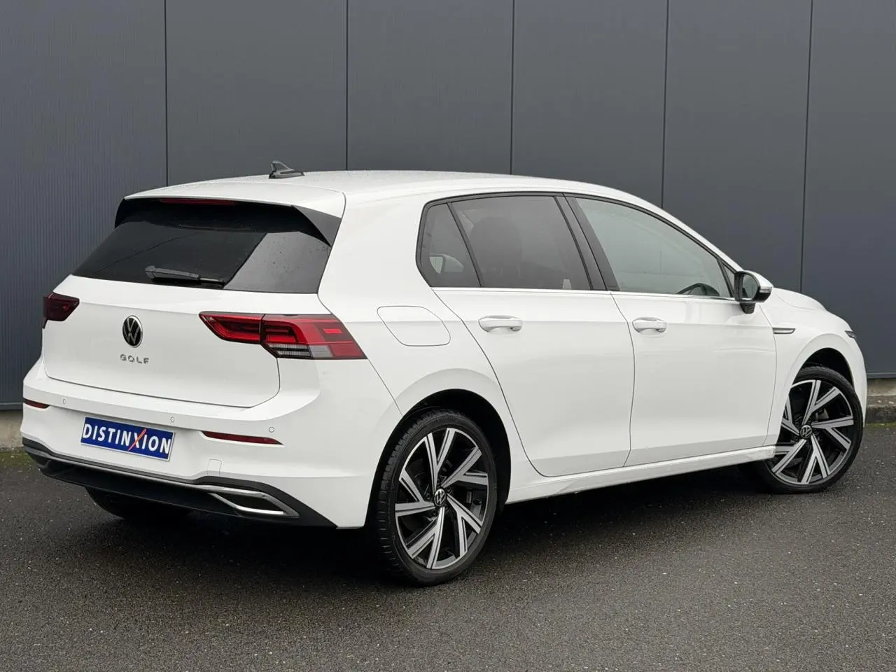 Volkswagen Golf VIII blanche vue 3/4 arrière droit avec jantes alliage 18 pouces et vitres arrière surteintées.