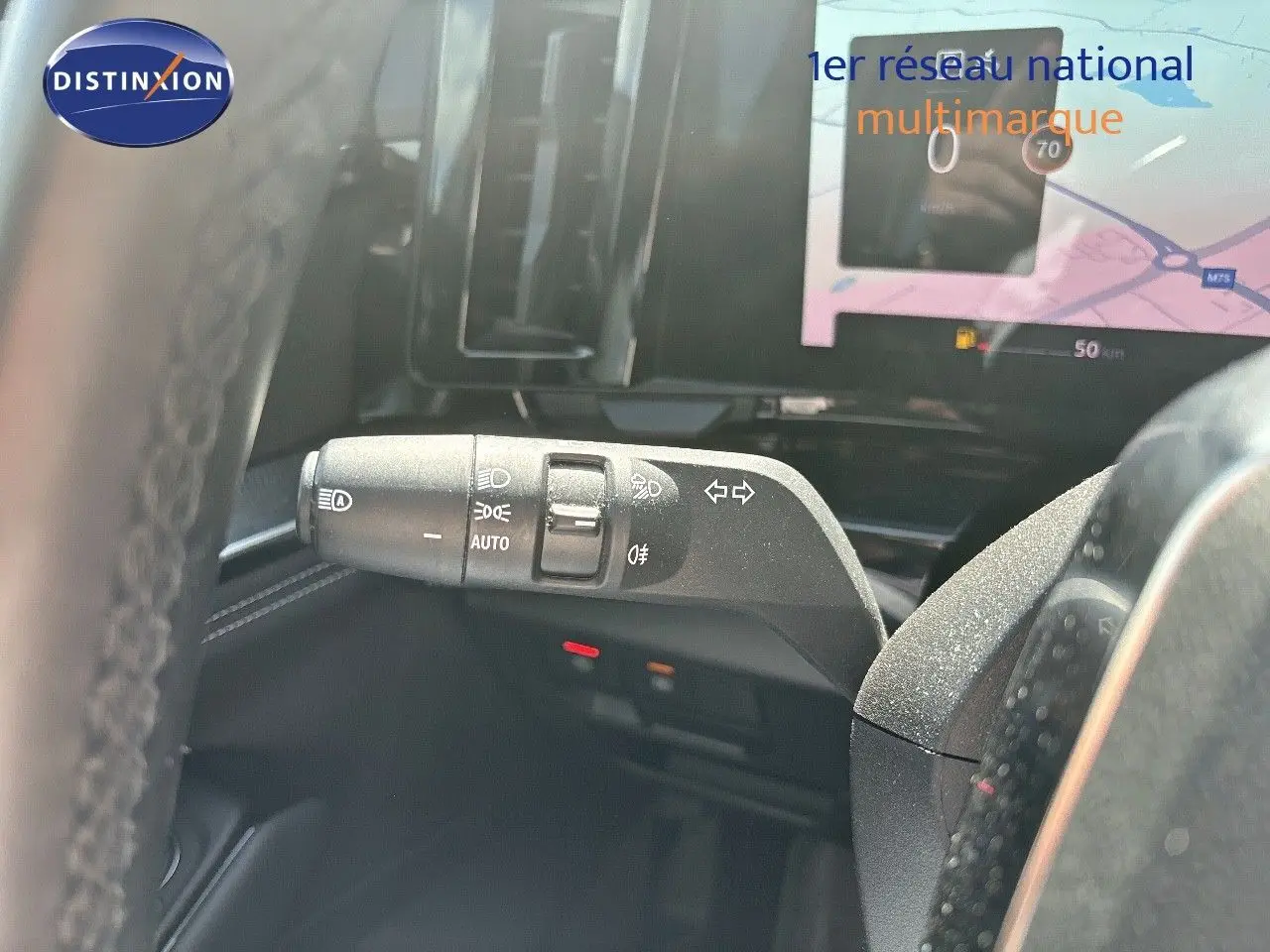 Gros plan sur la manette de clignotants et feux du Renault Austral gris schiste, avec écran tactile en arrière-plan.