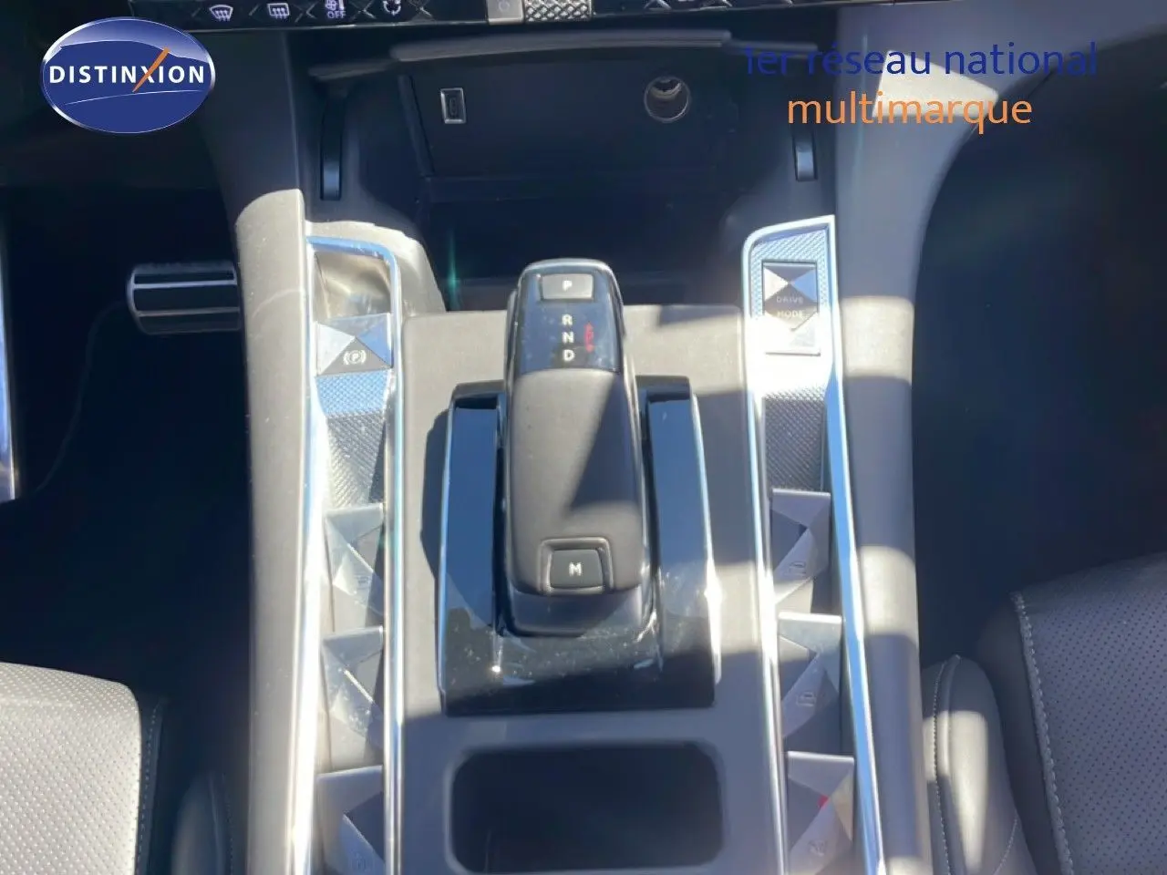 Vue rapprochée de la console centrale du DS7 2024 noir métal, avec levier de vitesse automatique et boutons triangulaires chromés.