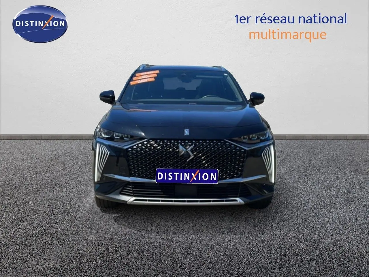 Vue frontale d’un DS7 noir métal 2024 avec calandre distinctive et feux LED verticaux allumés.