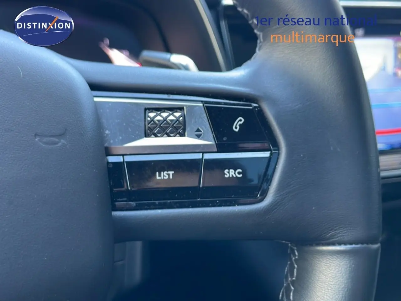 Gros plan sur les commandes gauche du volant en cuir noir du DS7 2024 noir métal, avec boutons LIST et SRC visibles.
