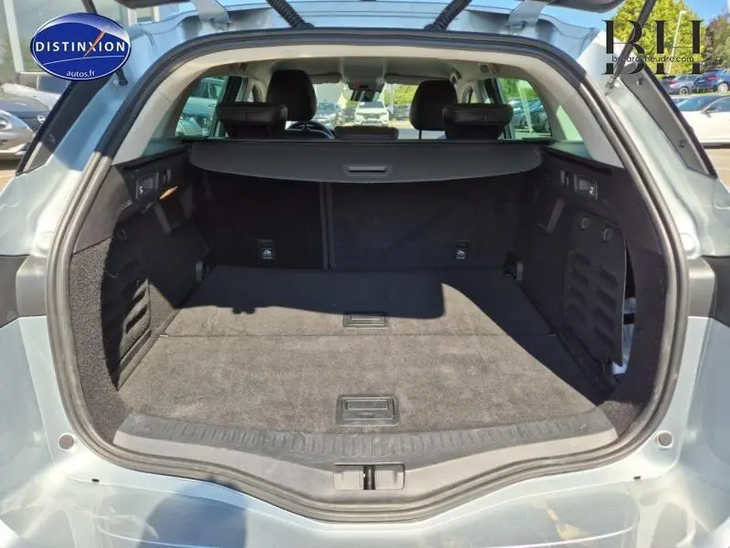 Coffre ouvert vu de l'arrière du Renault Mégane Break gris Titanium 2024, espace de chargement spacieux et tapis noir.