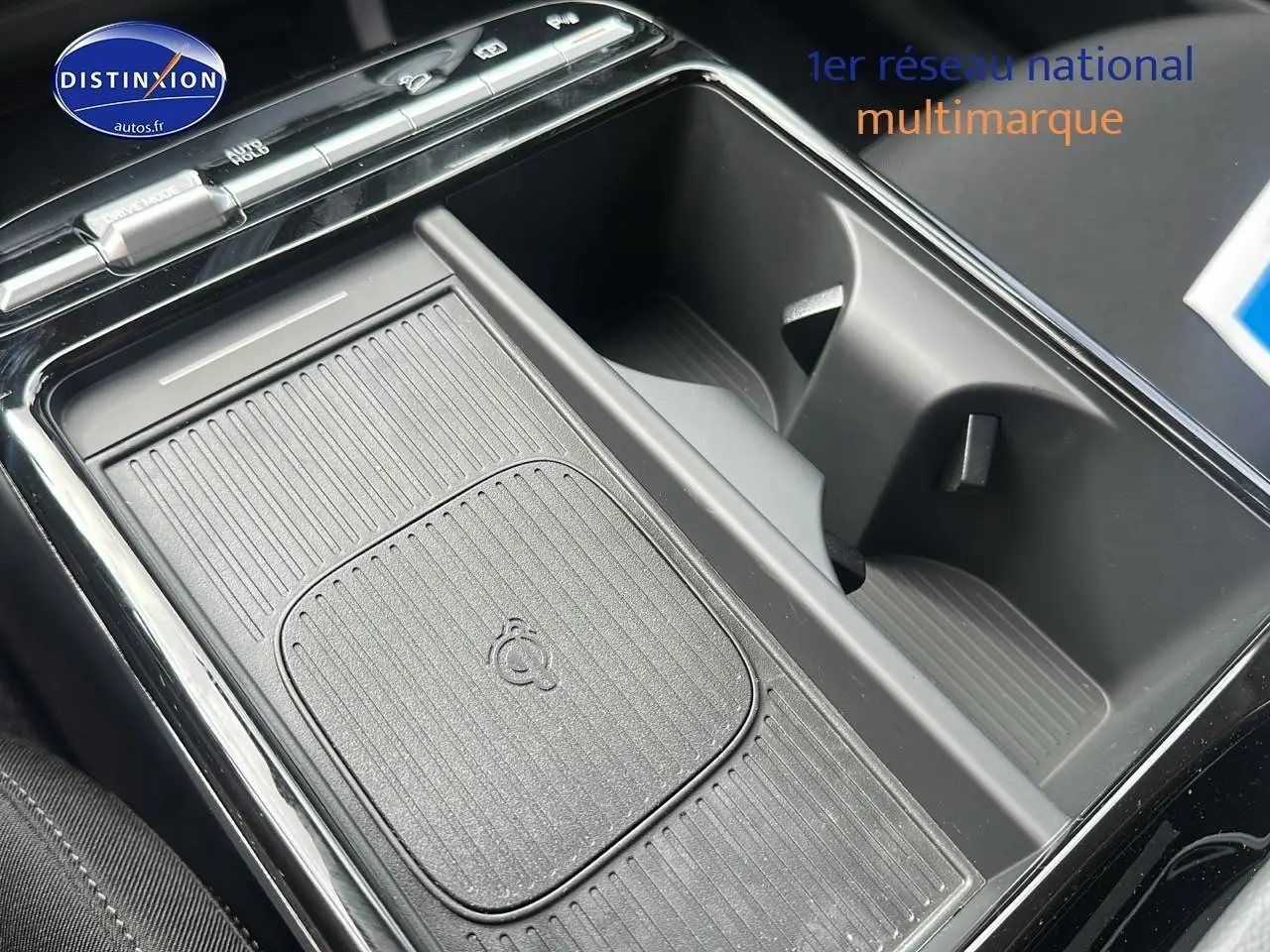 Gros plan sur la console centrale noire du Hyundai Tucson 2025 avec chargeur sans fil et porte-gobelets.