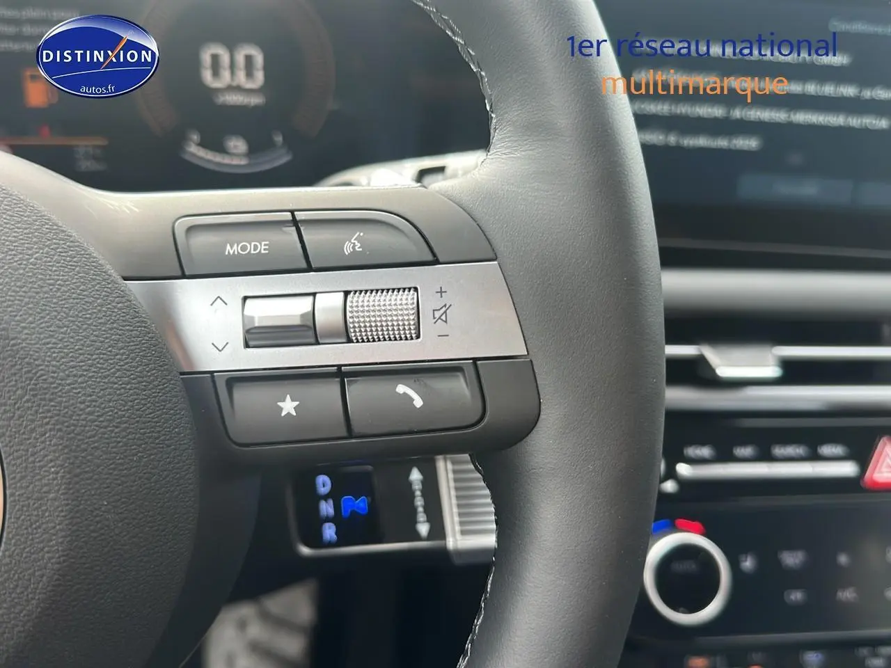 Gros plan sur le volant cuir multifonction du Hyundai Tucson blanc sérénité, avec commandes audio et tableau de bord flou en arrière-plan.