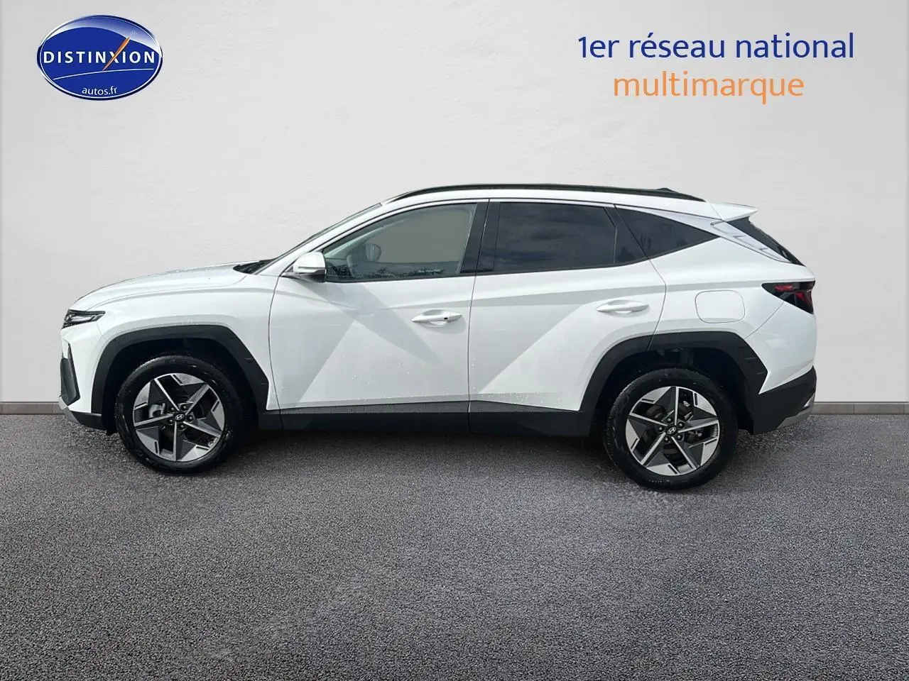 Profil côté gauche du Hyundai Tucson blanc sérénité 2025 avec jantes alliage et vitres teintées.