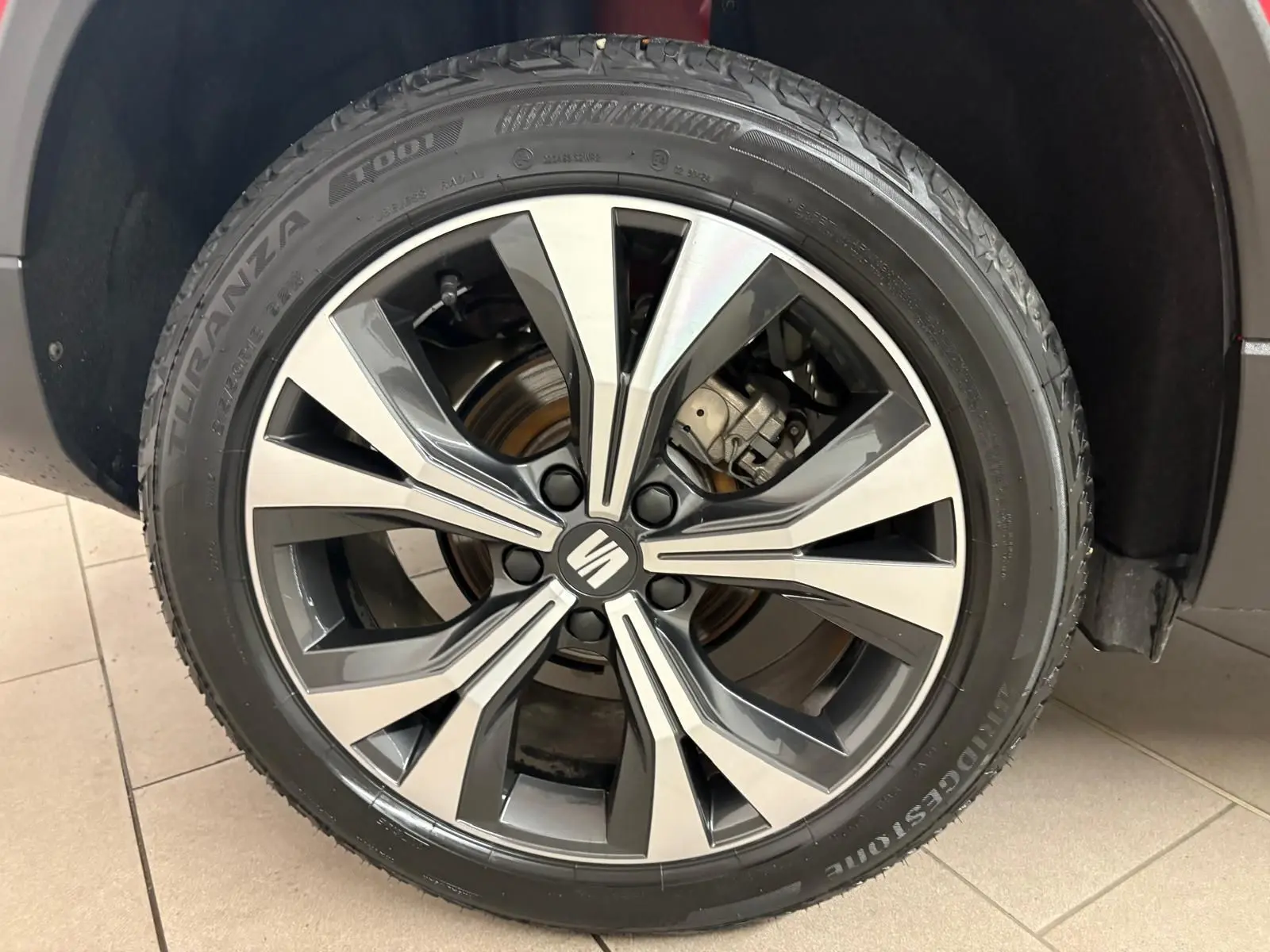 Gros plan sur la roue avant droite du SEAT Ateca 2024 Rouge Velvet avec jante alliage bicolore et logo central.