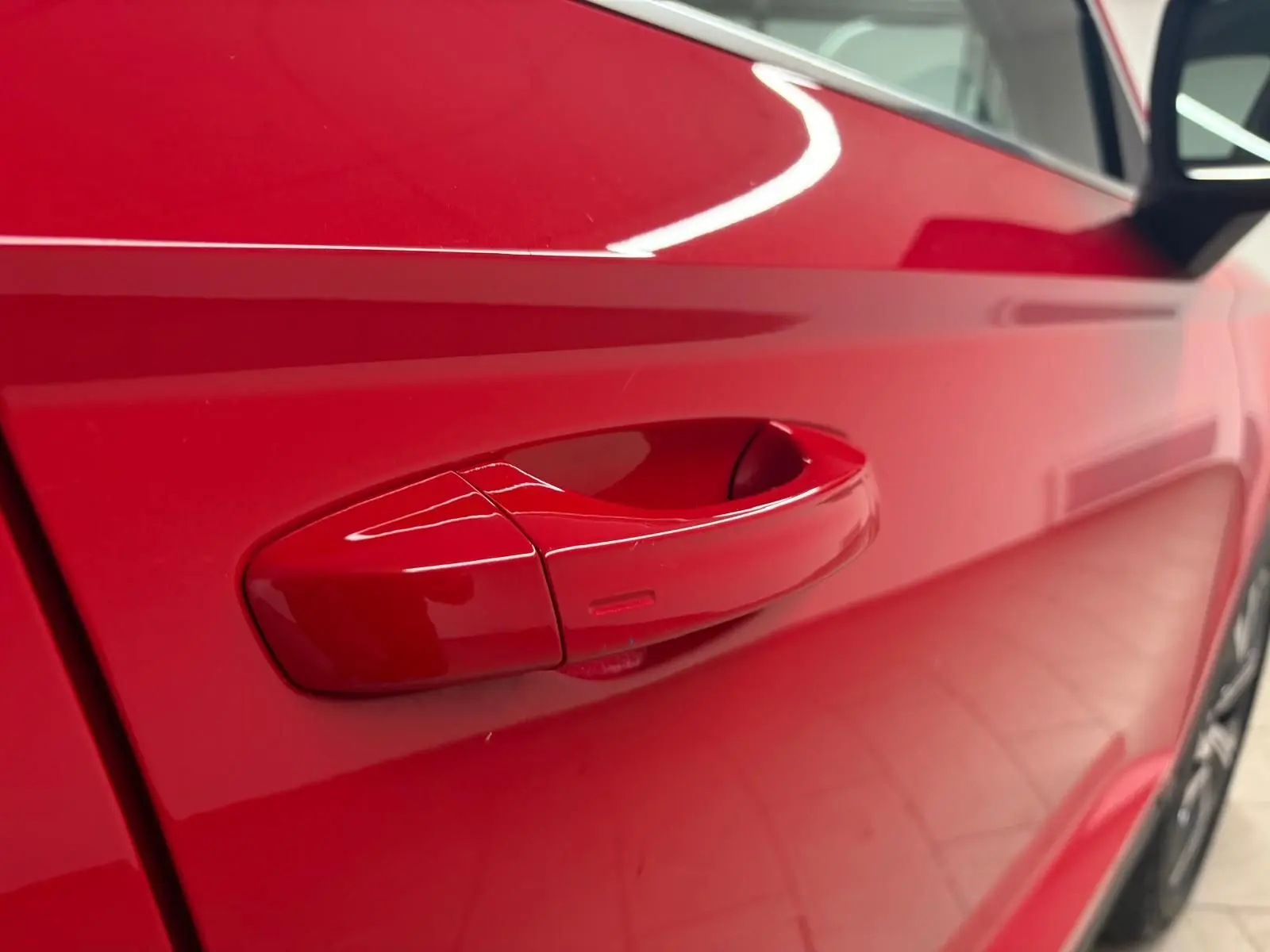 Poignée de porte côté droit rouge métallisée du SEAT Ateca 2024 vue en gros plan avec reflet lumineux.