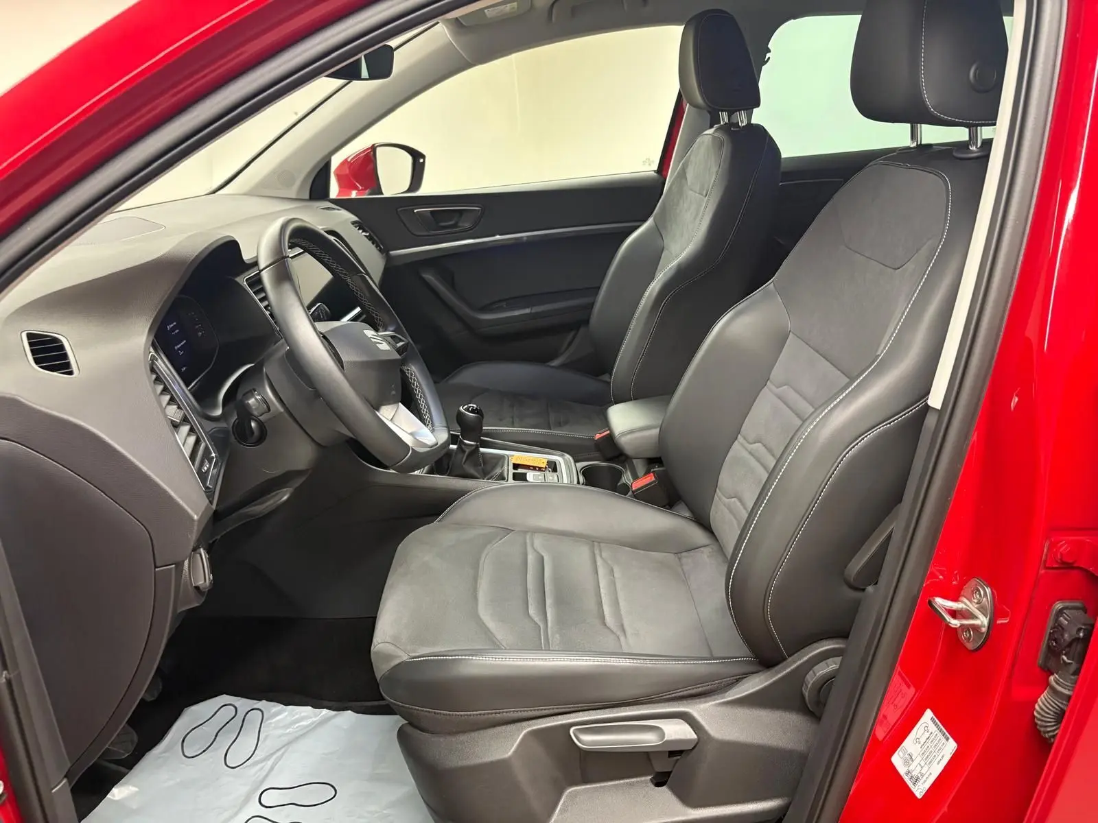 Vue intérieure côté conducteur du SEAT Ateca Rouge Velvet 2024, montrant les sièges en cuir noir et la boîte manuelle.