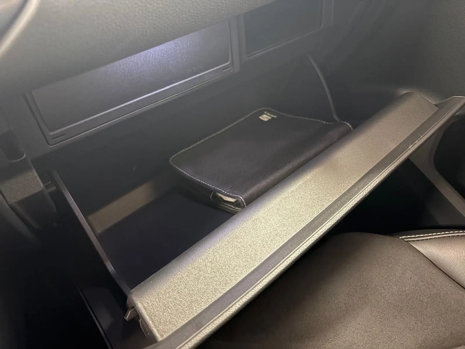Vue rapprochée de la boîte à gants ouverte du SEAT Ateca 2024 avec pochette noire à l’intérieur, intérieur noir.