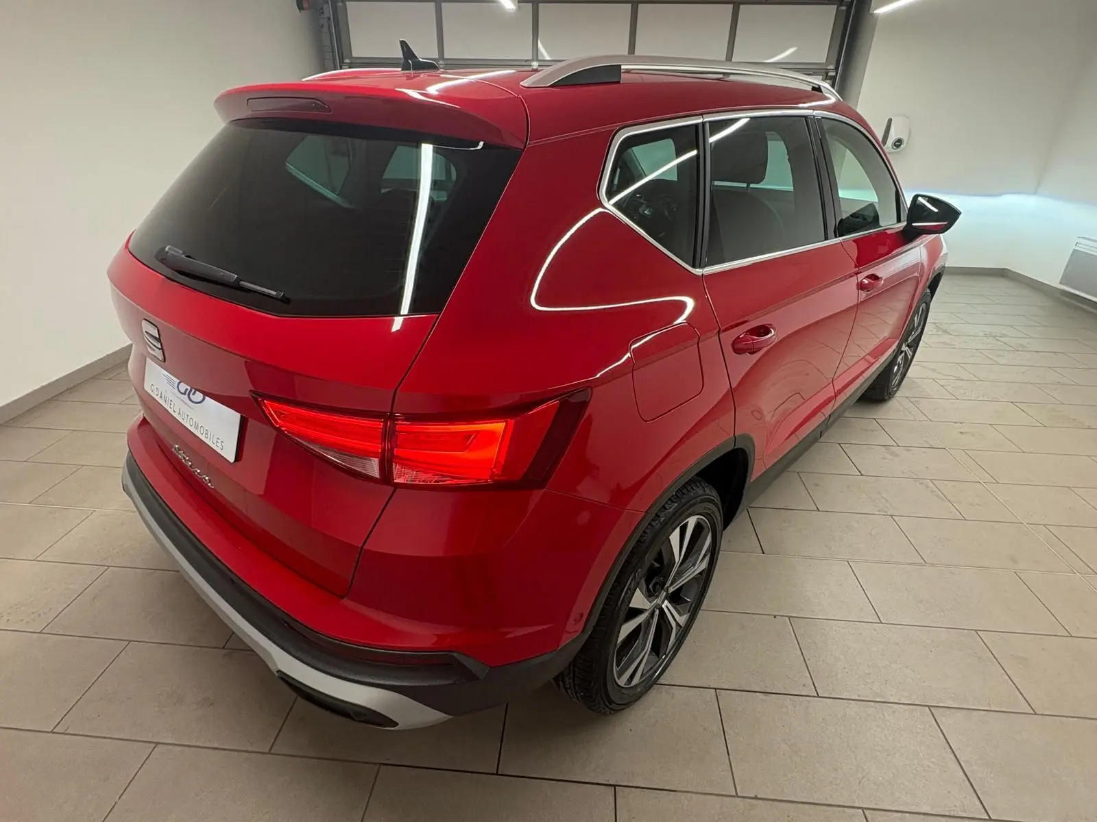 Vue 3/4 arrière droite du SEAT Ateca 2024 en Rouge Velvet métallisé, soulignant ses feux arrière allumés et ses jantes alliage.