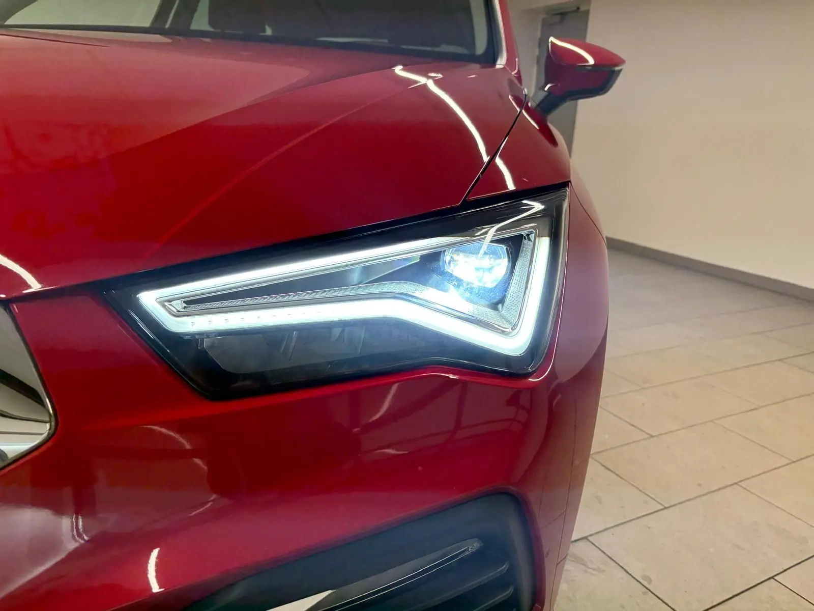 Gros plan sur le phare avant gauche allumé d’un SEAT Ateca 2024 Rouge Velvet avec peinture métallisée.