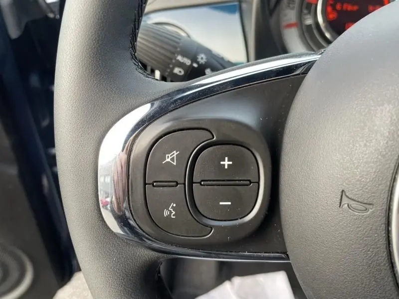 Gros plan sur les commandes de volume et de coupure du son au volant d’une Fiat 500 bleu métal 2023.