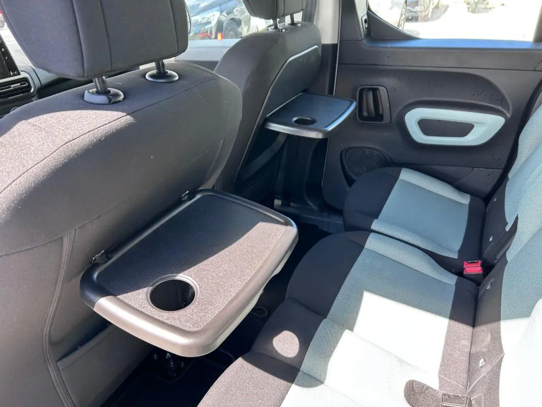 Vue intérieure côté droit des sièges arrière gris et noir d'un Citroën Berlingo avec tablettes rabattables fixées aux dossiers.