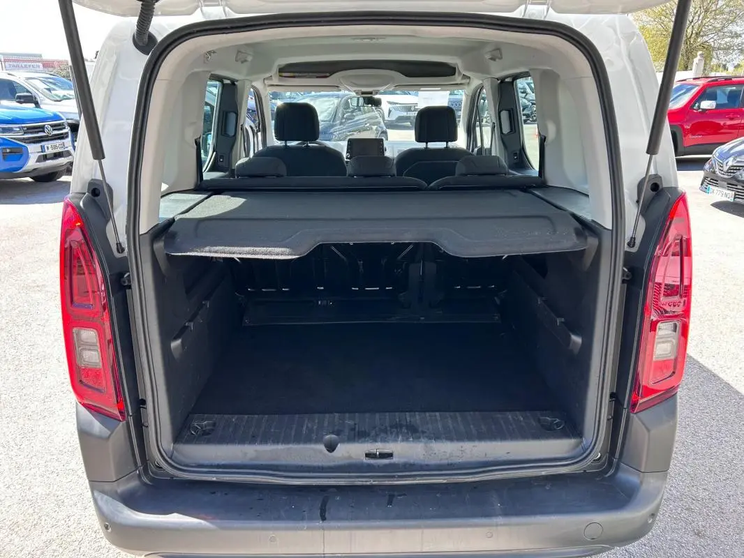 Vue arrière ouverte du coffre d'un Citroën Berlingo blanc 2020, montrant l'espace de chargement et les sièges arrière.