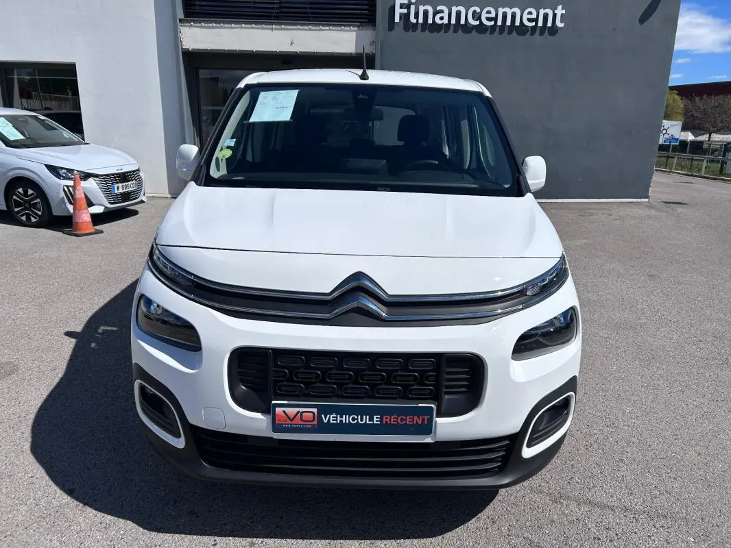 Vue avant d'un Citroën Berlingo blanc avec calandre noire et barres de toit visibles en extérieur.