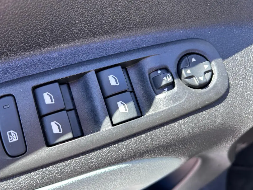 Gros plan sur les commandes des vitres et rétroviseurs électriques côté conducteur du Citroën Berlingo blanc 2020.