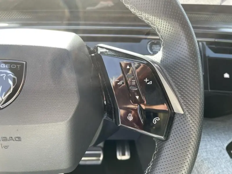 Gros plan sur la partie droite du volant perforé gris foncé du Peugeot 3008 2024 hybride avec commandes intégrées.