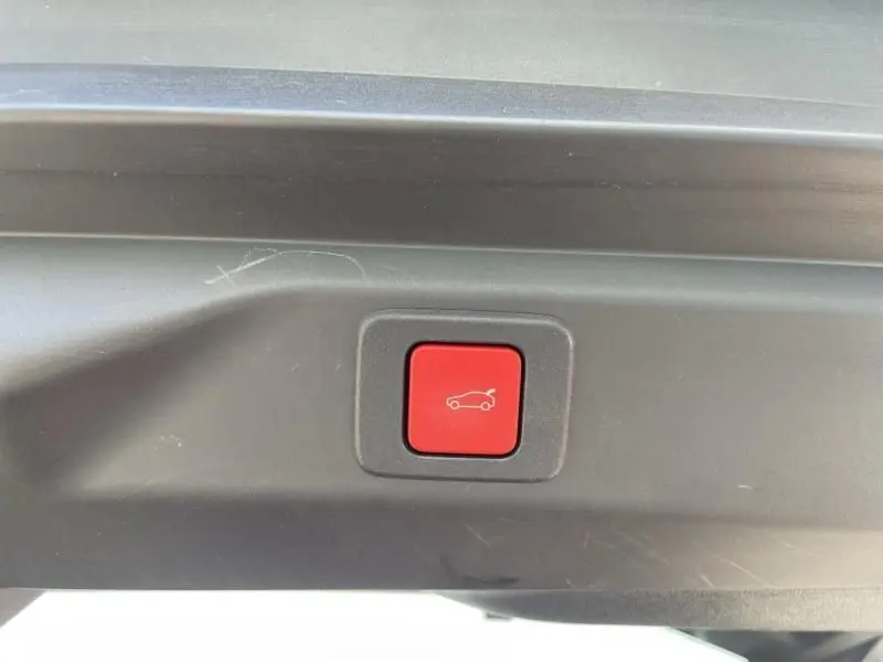 Bouton rouge d'ouverture électrique du hayon sur le coffre d'un Peugeot 3008 Nouveau gris foncé 2024.