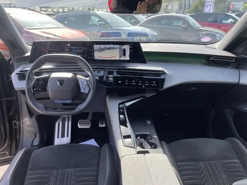 Vue intérieure avant du Peugeot 3008 2024 hybride, tableau de bord moderne avec écran large et volant compact noir.