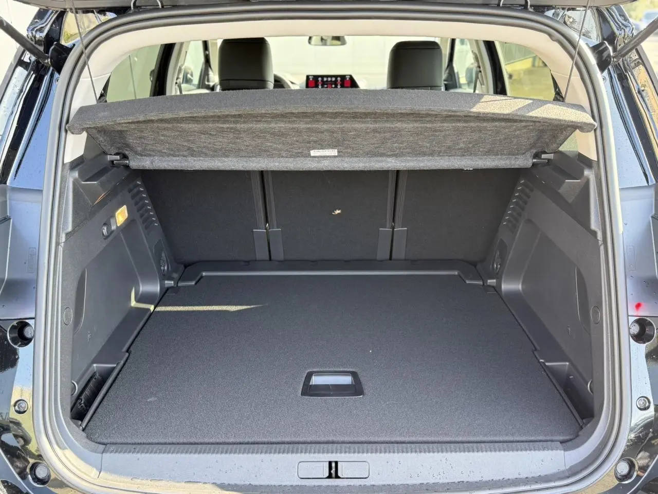 Vue arrière du coffre ouvert d'un Citroën C5 Aircross noir Perla, montrant l'espace de chargement et la tablette cache-bagages.