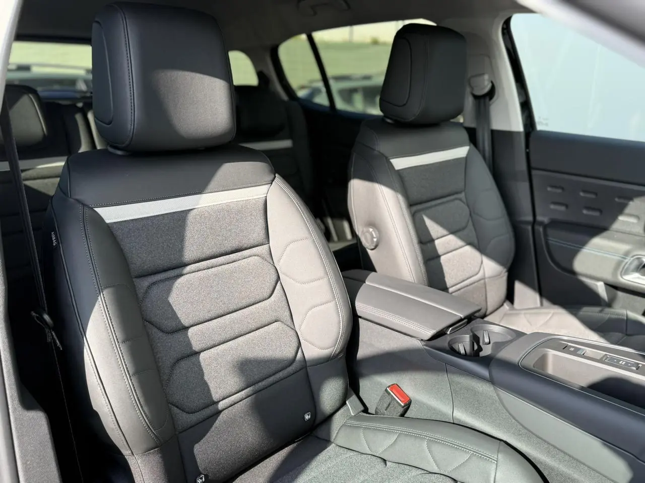 Vue intérieure de face des sièges avant gris foncé avec tissu et cuir, accoudoir central et console d'une Citroën C5 Aircross 2025.