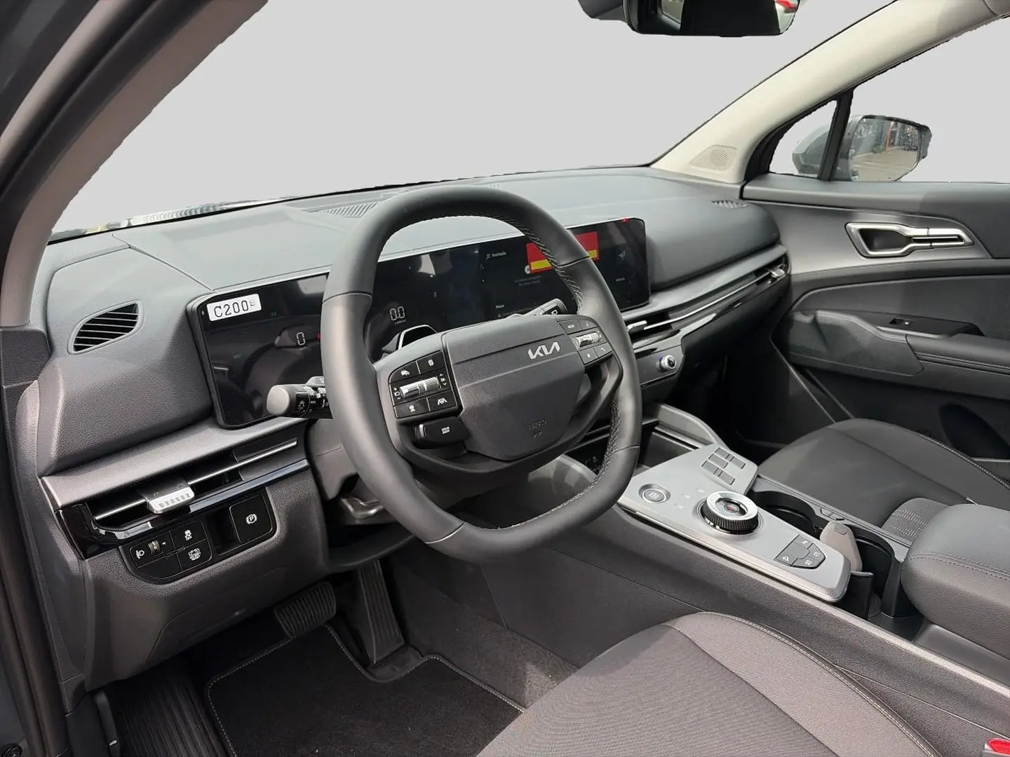 Intérieur avant du Kia Sportage 1.6 hybride 2026 vu côté conducteur, avec volant cuir multifonction et tableau de bord numérique.