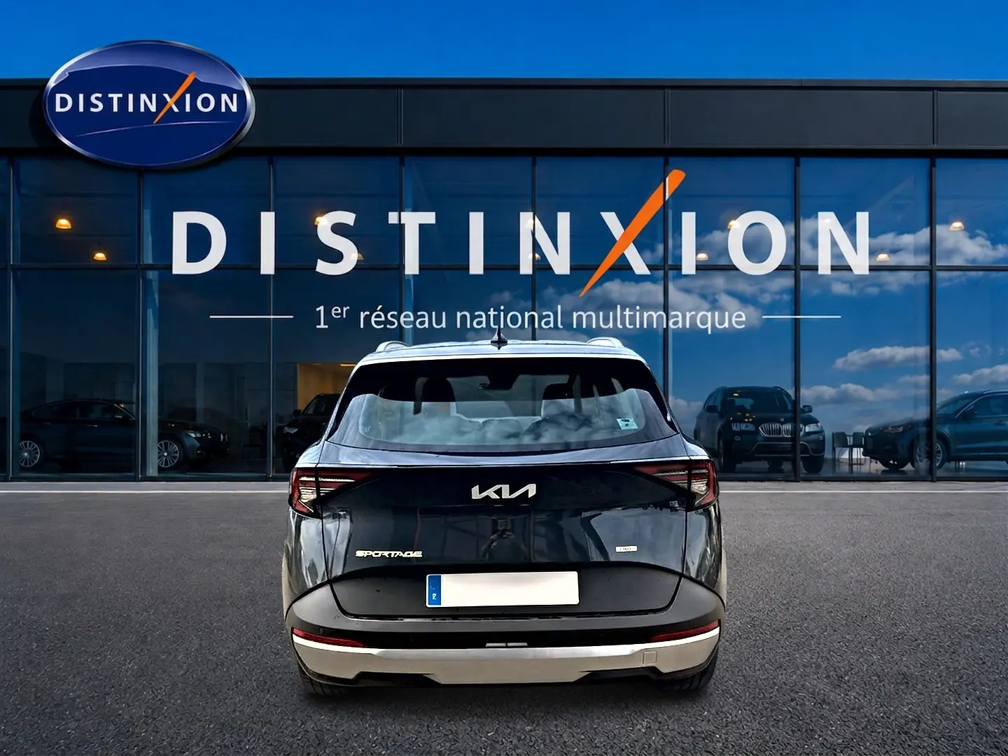 Vue arrière d'un KIA SPORTAGE 1.6 hybride gris eclipse, avec feux arrière LED et barres de toit visibles.