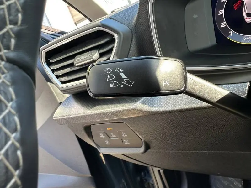 Gros plan sur la commande des feux et clignotants à gauche du volant dans l’habitacle d’un SEAT LEON ST bleu saphir métallisé.