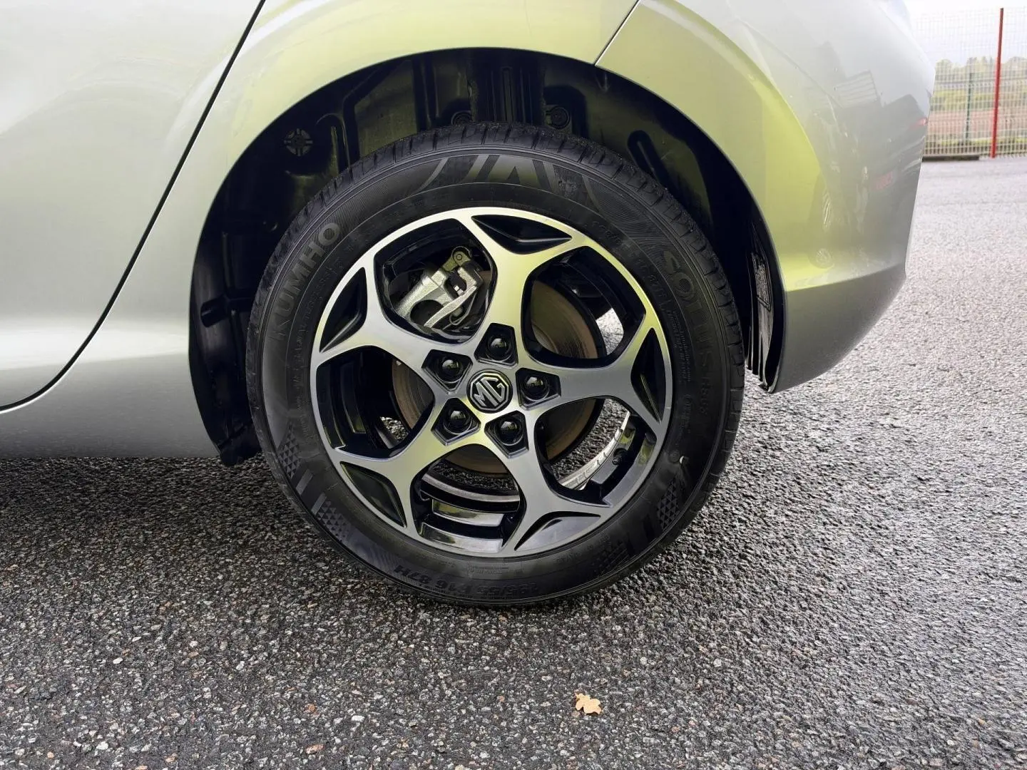 Gros plan sur la roue arrière droite d'une MG3 Cosmic Silver métallisé avec jante alliage noire et logo MG au centre.