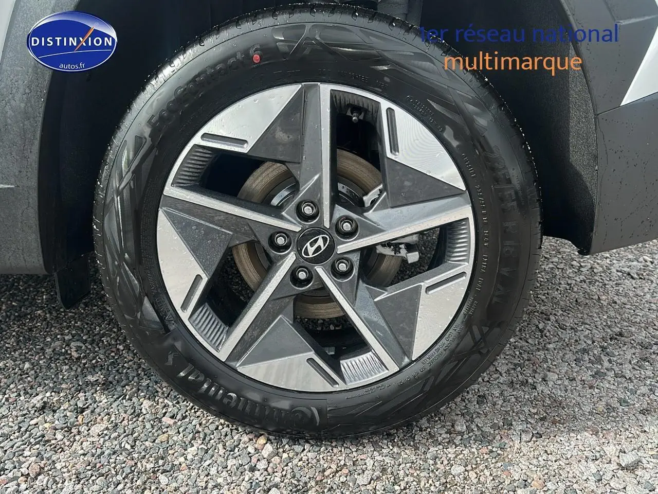 Gros plan sur la roue avant gauche du Hyundai Tucson blanc Sérénité avec jante alliage 18 pouces design moderne.