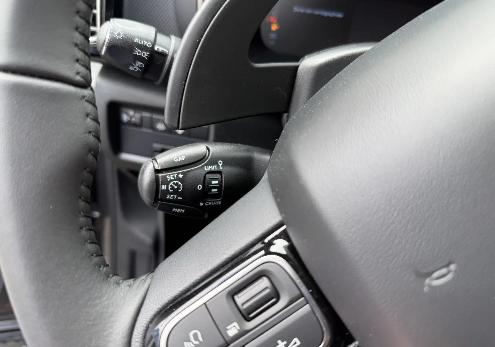 Gros plan sur la commande de régulateur de vitesse à gauche du volant cuir noir du Citroën C5 Aircross 2025.