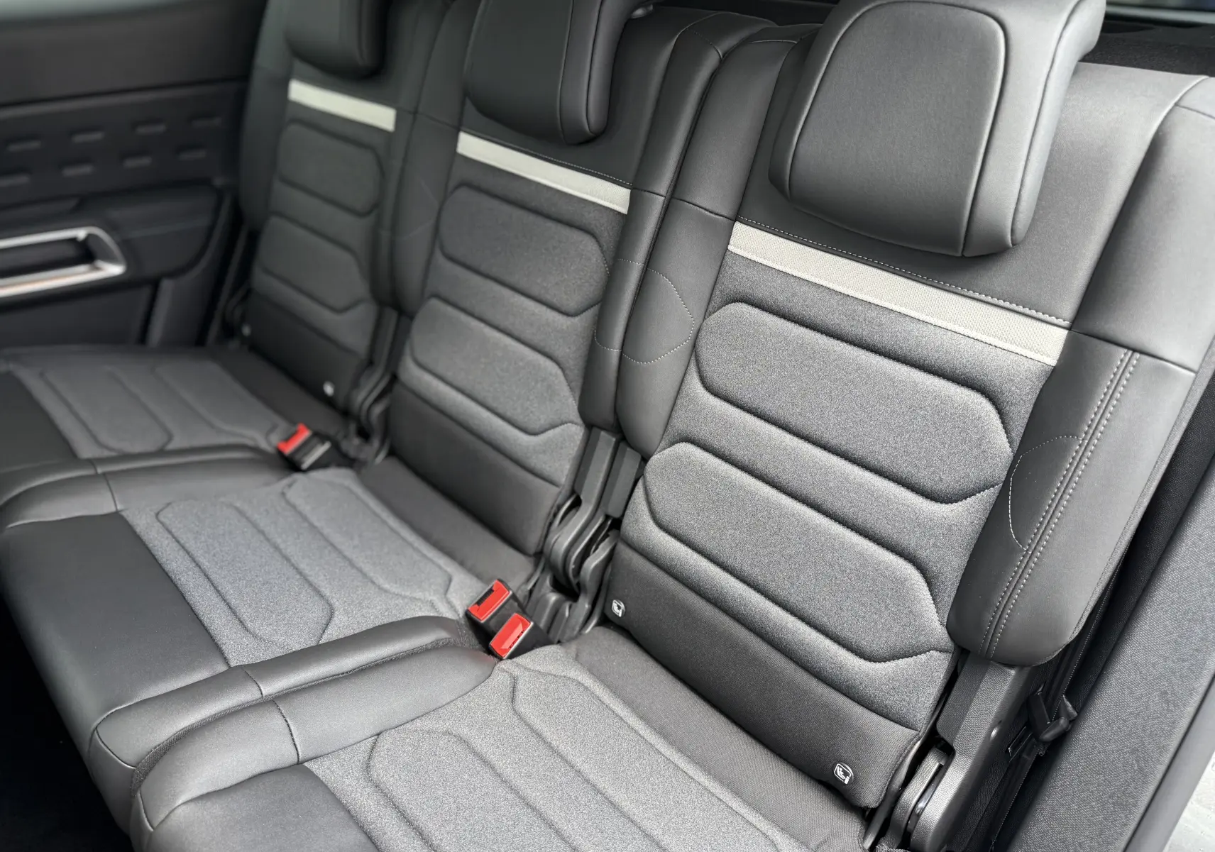 Vue rapprochée des sièges arrière en cuir noir et tissu gris du Citroën C5 Aircross 2025, avec ceinture rouge visible.