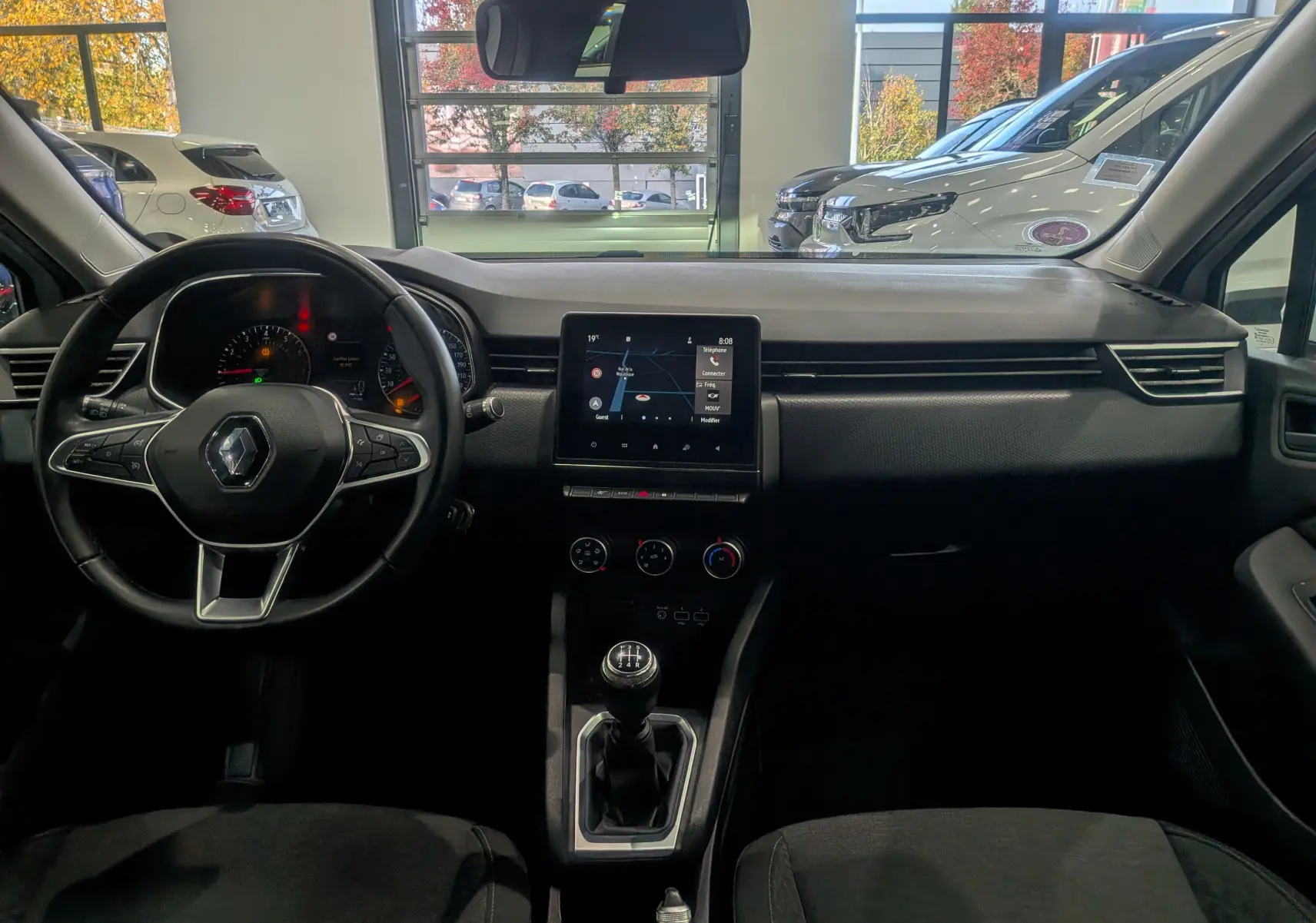 Vue intérieure avant de la Renault Clio V TCe 100 Business 2020, tableau de bord noir avec écran tactile et boîte manuelle.