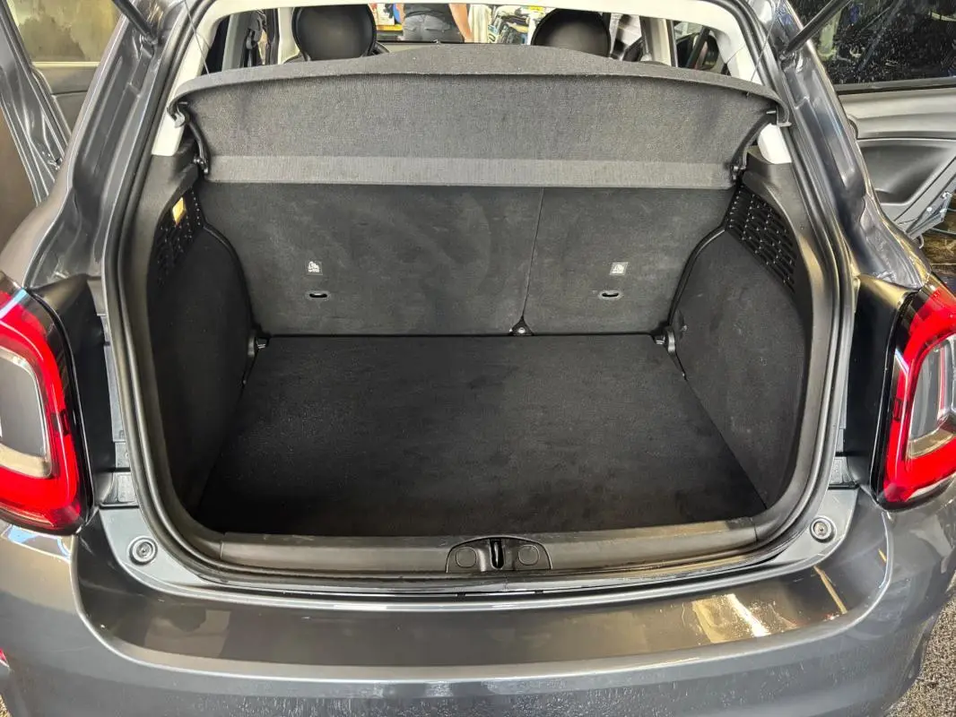 Coffre ouvert vu de l'arrière d'une FIAT 500X MY23 gris, montrant l'espace de chargement vide et la plage arrière.