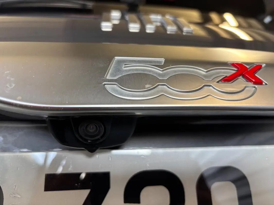 Gros plan sur le logo 500X gris métallisé avec caméra de recul intégrée au-dessus de la plaque d’immatriculation.