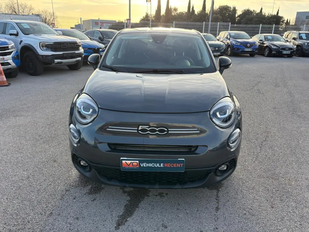 Vue avant d'une FIAT 500X MY23 gris, avec phares ronds et calandre distinctive, stationnée en extérieur.