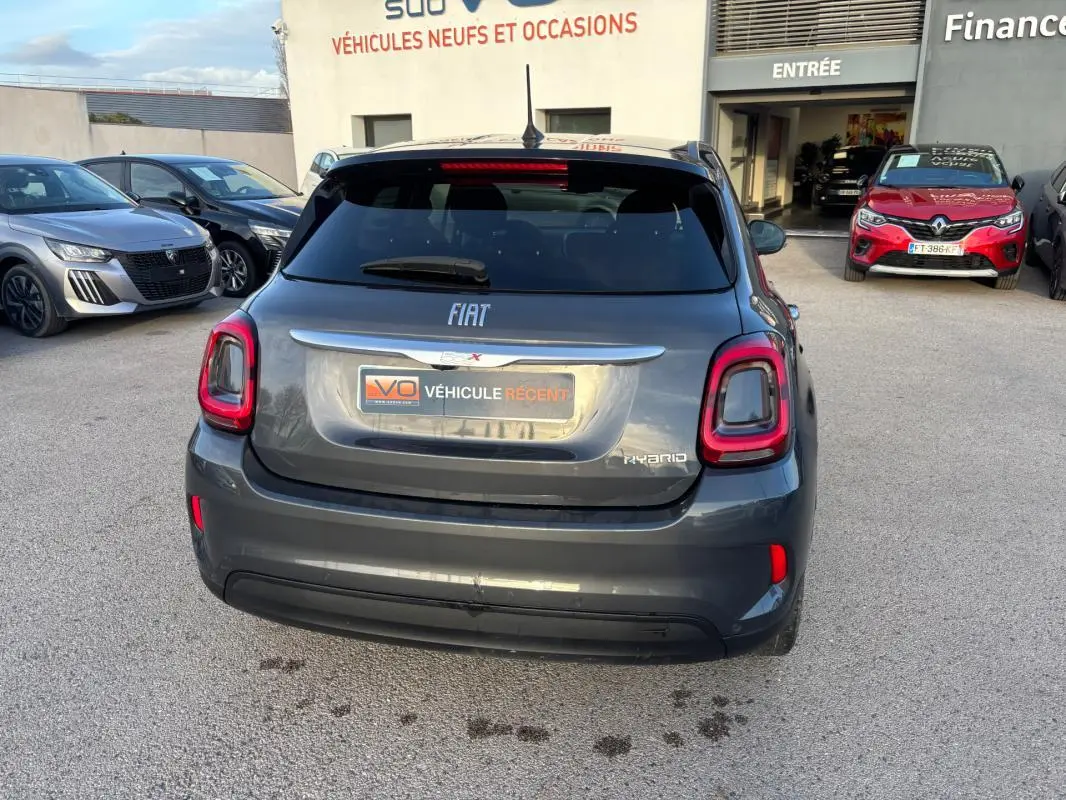 Vue arrière d'une FIAT 500X MY23 gris métallisé avec feux arrière LED et logo Hybrid visible.