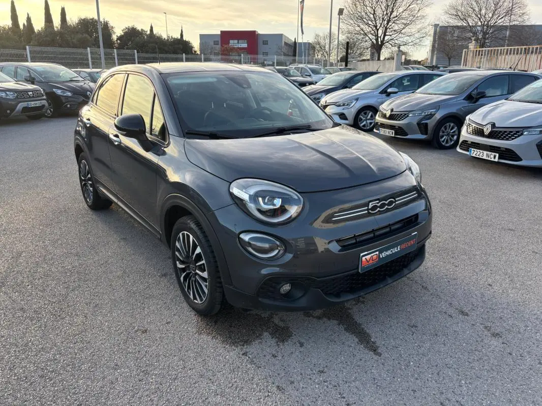 Vue 3/4 avant d'une FIAT 500X gris métallisé avec jantes 16 pouces et phares ronds caractéristiques.