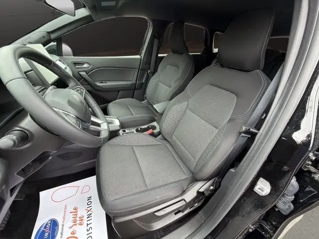 Intérieur avant droit du Renault Symbioz noir 2025, sièges tissu noir avec surpiqûres bleues et volant multifonction.