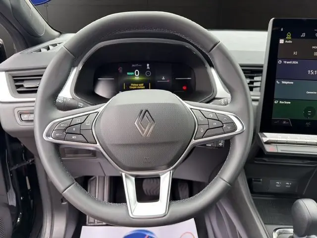 Vue frontale du volant noir de la Renault Symbioz E-Tech Full Hybrid 145 Evolution avec tableau de bord numérique et écran tactile.