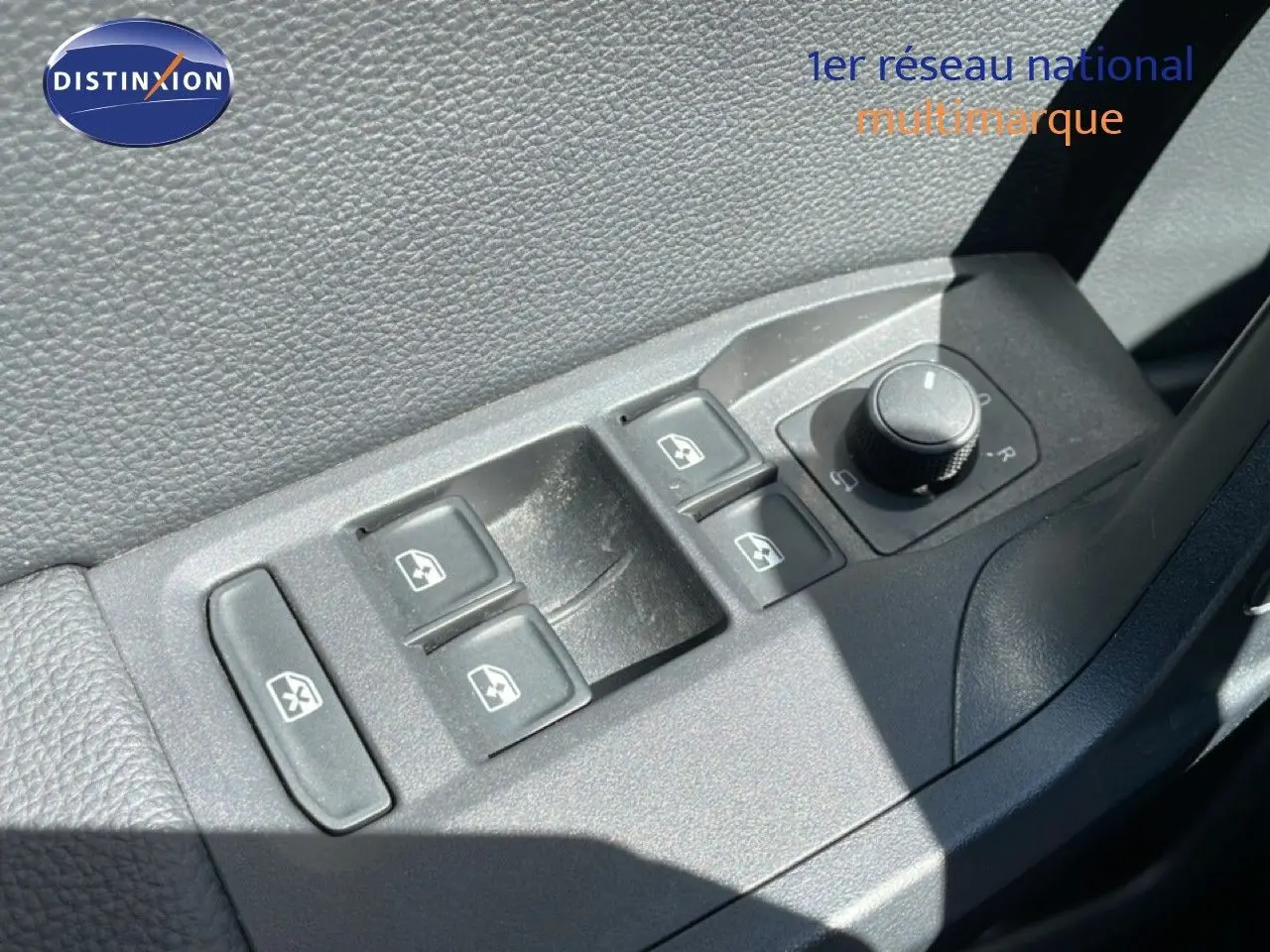 Gros plan sur les commandes de lève-vitres et réglage des rétroviseurs côté conducteur du SEAT Arona noir intérieur.