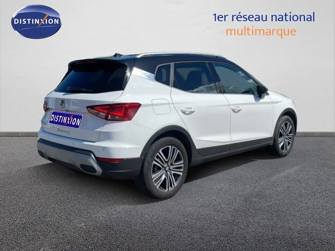 Vue 3/4 arrière droite d’un SEAT Arona blanc avec toit noir, jantes alliage et détails noirs contrastants.