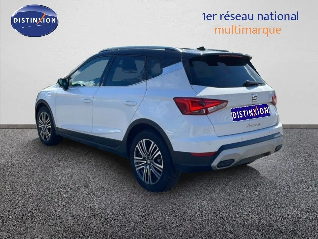 Vue 3/4 arrière droite d'un SEAT Arona 2025 blanc magnétique avec toit noir et jantes alliage.