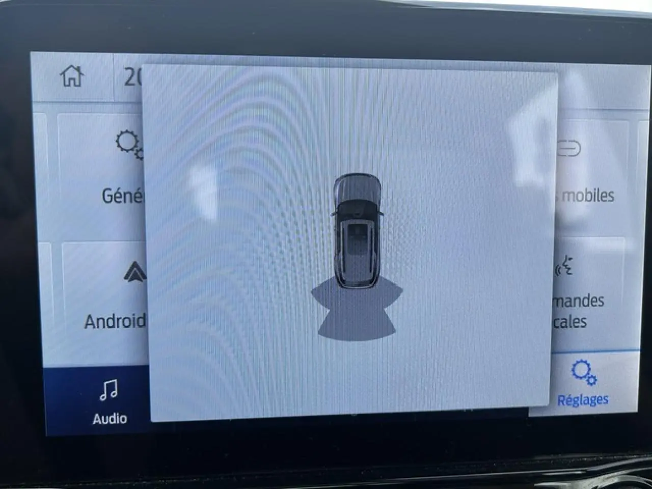 Affichage écran intérieur montrant la vue de dessus du Ford Puma gris Magnetic en mode aide au stationnement.