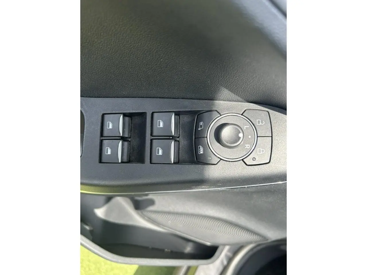 Gros plan sur les commandes de lève-vitres et réglage des rétroviseurs côté conducteur du Ford Puma gris Magnetic 2022.