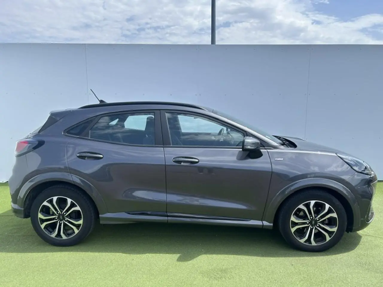Ford Puma gris Magnetic vue de profil côté gauche, avec jantes alliage et détails noirs sur les passages de roues.
