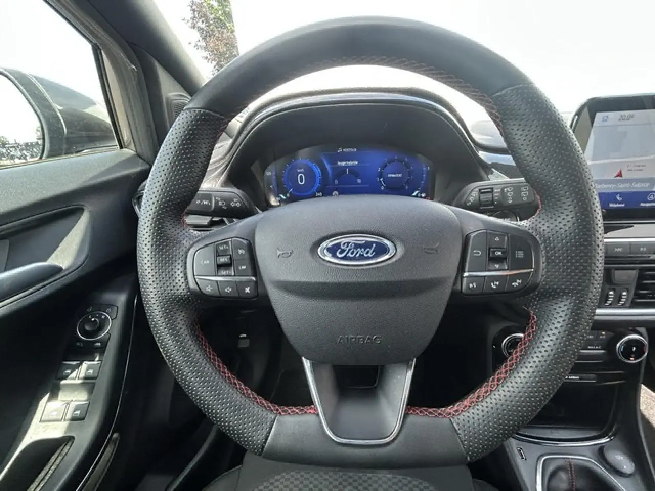 Vue intérieure centrée sur le volant perforé noir avec surpiqûres rouges de la Ford Puma ST Line 2022.