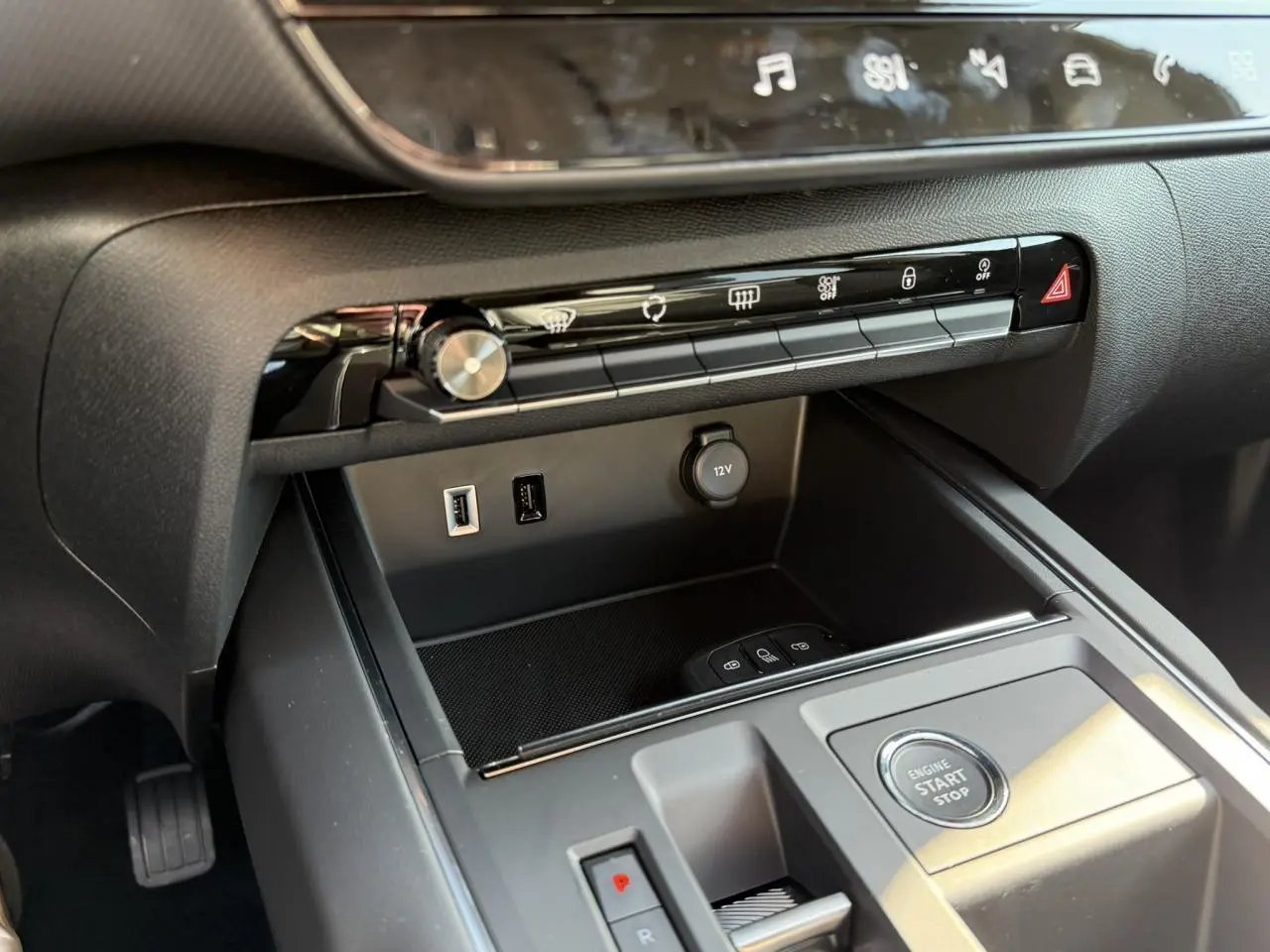 Détail de la console centrale noire du Citroën C5 Aircross 2025 avec boutons de commande et prise 12V vus de côté droit